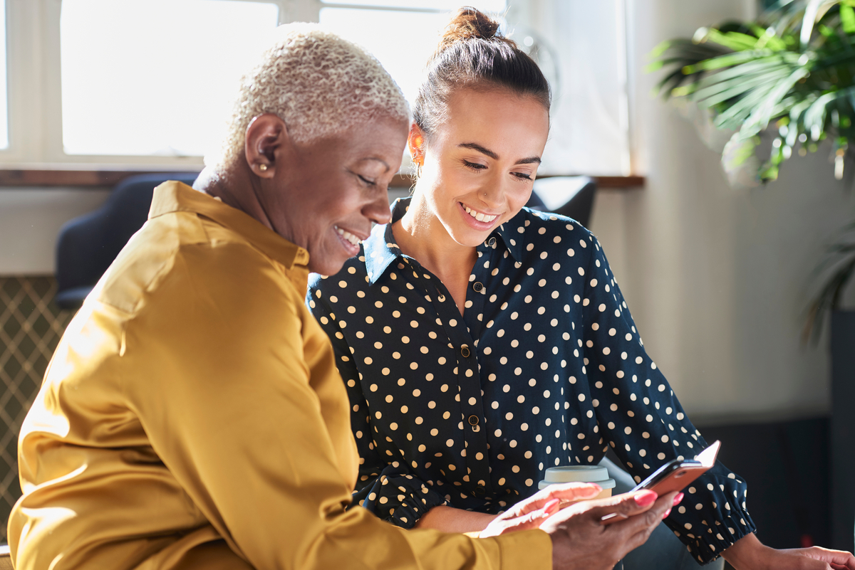 senior woman and young woman looking at mobile phone