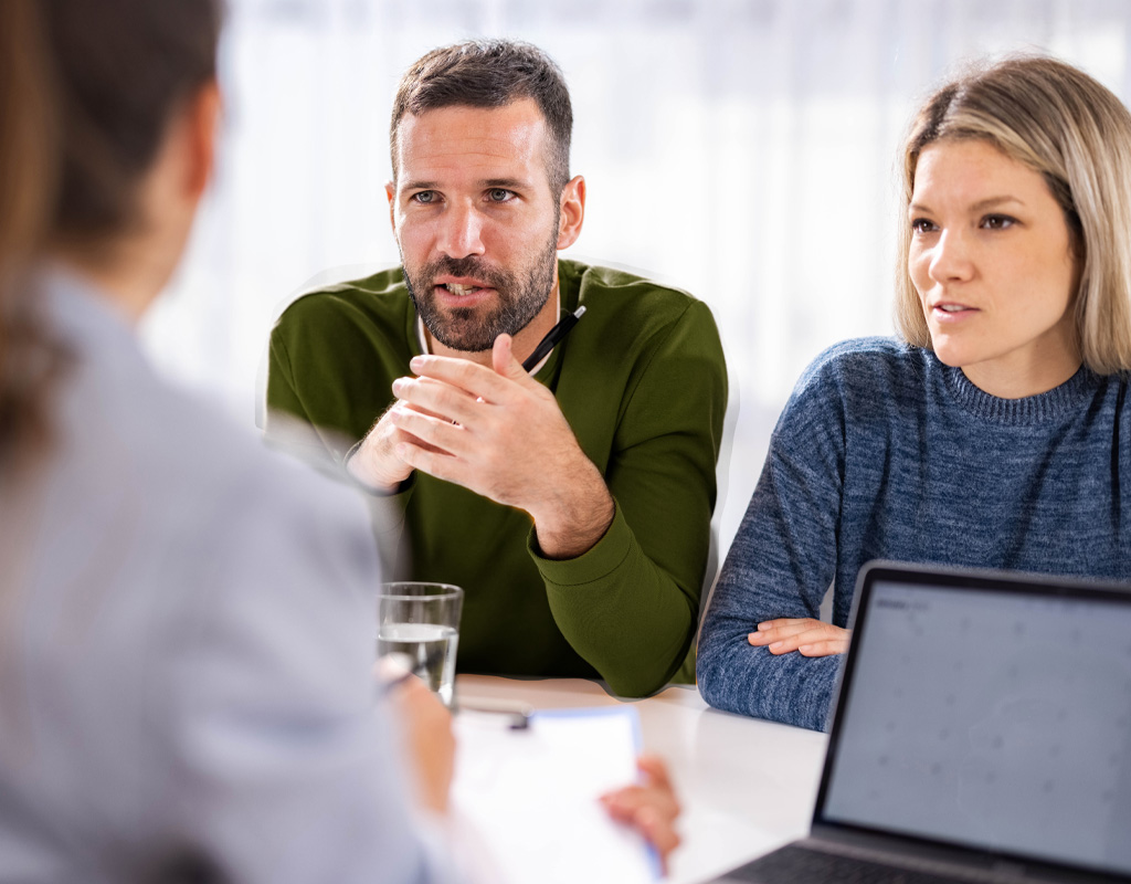 Group of three people having a serious conversation at a desk. There is one provider and a couple