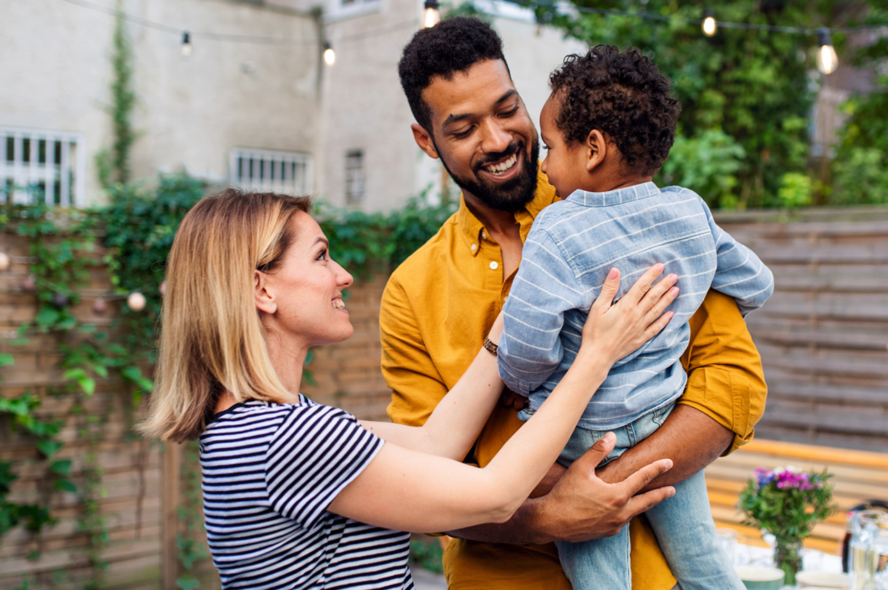 Three generations family meeting and talking at dinner party outdoors in backyard.