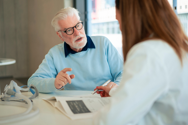 Senior patient discussing with doctor at desk in hospital