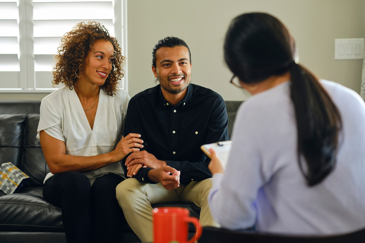 Couple sitting on a couch while talking to a genetic counselor.