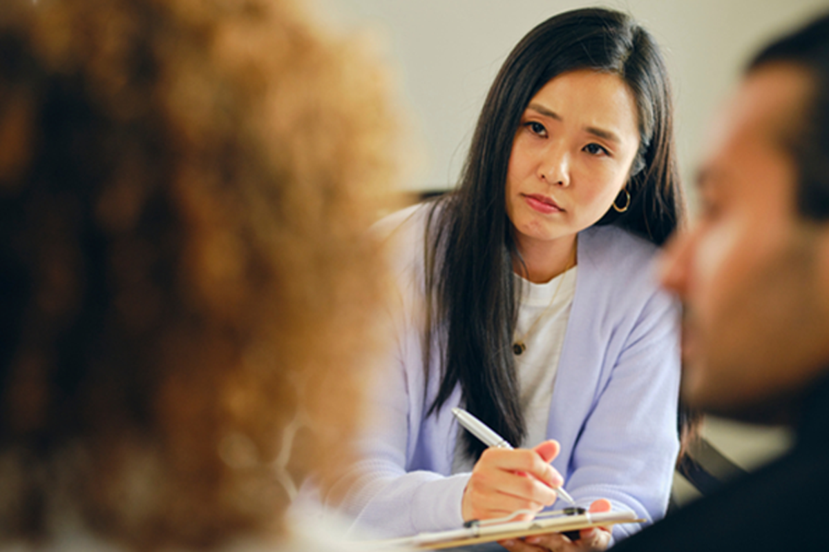 Provider writing on a clipboard while listening to a couple speak